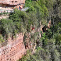 Ein Höhenretter seilt sich an den roten Felsen in großer Höhe ab.