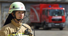 Feuerwehrfrau vor Einsatzwagen. Foto: BDBOS/Wilke