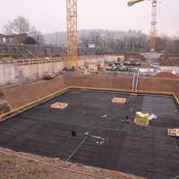 Panorameblick auf eine Baustelle mit Gruben, Bewehrung und Kränen