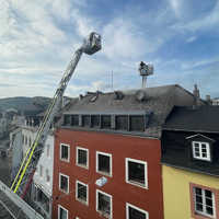 Aus der Dachgeschosswohnung dringt Qualm, Feuerwehrleuten überwachen die Situation.