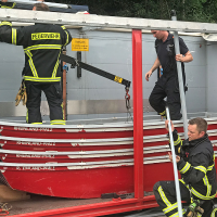Drei Feuerwehrmänner entladen die Boote aus dem Abrollbehälter.