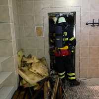 Feuerwehrmänner gehen in einen Saunabereich, neben der Tür liegt verbranntes Material.