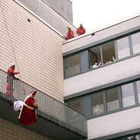 Ein als Nikolaus verkleideter Feuerwehrmann seilt sich an einem Krankenhaus ab