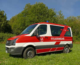 Das Mannschaftstransportfahrzeug der Freiwilligen Feuerwehr Irsch steht auf einer Wiese.