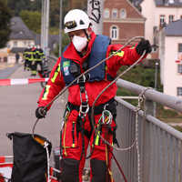 Ein Höhenretter befestigt Seile an einem Geländer.