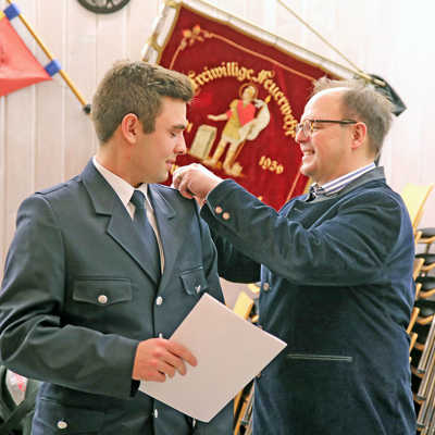 Dezernent Ralf Britten (r.) befördert Luca Linz von der Freiwilligen Feuerwehr Zewen vom Feuerwehrmann zur Ausbildung zum Feuerwehrmann und heftet ihm die Schulterklappen an.