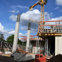 Zwei halbfertige Stahlbetonsäulen stehen auf einer Baustelle separat neben weiteren Gebäudeteilen.