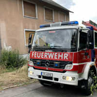 Das Hilfeleistungslöschgruppenfahrzeug der Freiwilligen Feuerwehr Olewig steht neben einem Haus.