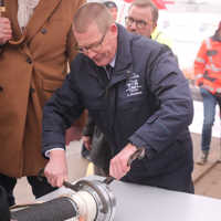 Andreas Kirchartz trägt eine Uniformjacke und verschließt die Zeitkapsel mit zwei Werkzeugen
