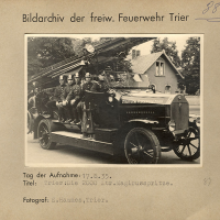 Schwarz-weiß Foto: Die 2000 Liter Magirusspritze ist gemeinsam mit der Feuerwehrbesatzung auf einem Auto verladen.